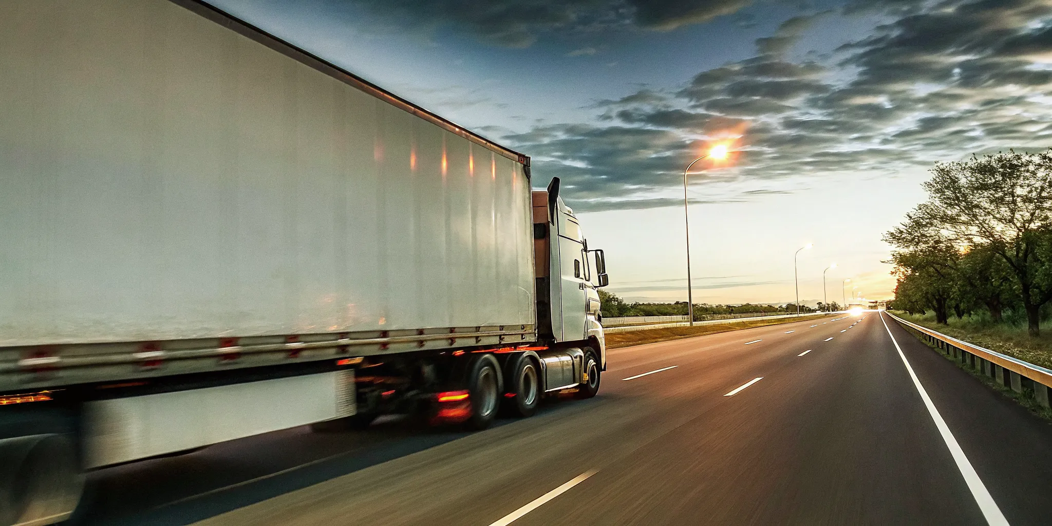 Semi truck on highway at dusk with motion blur, representing expedited freight shipping